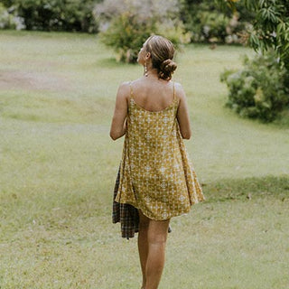 Wings Hawaii model wearing trapeze mini dress in ulu and plumeria print in marigold