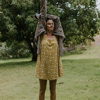 Wings Hawaii model wearing trapeze mini dress in ulu and plumeria print in marigold