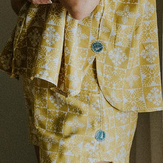 Model wearing Wings Hawaii retro pocket shorts and boxy buttun-up blouse in quilted ulu and plumeria print in marigold