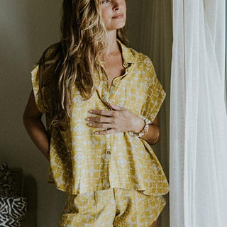 Model wearing Wings Hawaii boxy button-up blouse and retro pocket shorts in quilted ulu and plumeria print in marigold
