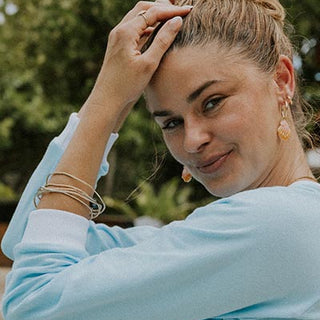 Model wearing charm hoop earrings adorned with Hawaiian sunrise shells in gold