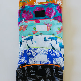 A collection of foldable adventure pouches in various colors and patterns, laid out flat.