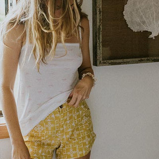 Model wearing Wings Hawaii retro pocket shorts in quilted ulu and plumeria print in marigold