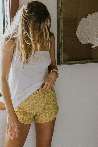 Model wearing Wings Hawaii retro pocket shorts in quilted ulu and plumeria print in marigold