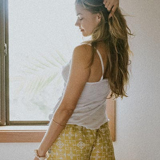 Model wearing Wings Hawaii retro pocket shorts in quilted ulu and plumeria print in marigold