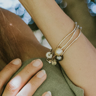 A gold hammered bracelet featuring a south seas pearl