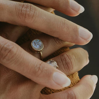 A moonstone carved in the shape of a sleeping moonfaced bezel set in a 14K yellow Gold ring