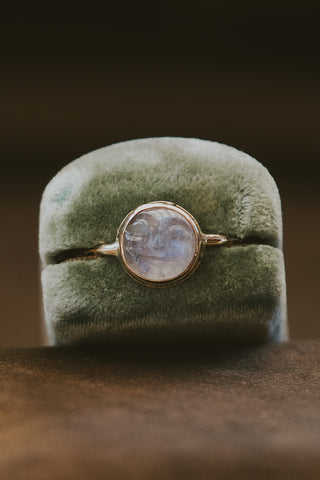 A moonstone carved in the shape of a sleeping moonfaced bezel set in a 14K yellow Gold ring
